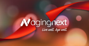 agingnext logo behind a red ribbon for a ribbon cutting event